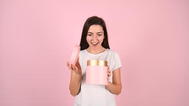 Portrait d'une jeune femme souriante heureuse ouvrant une boîte cadeau isolée