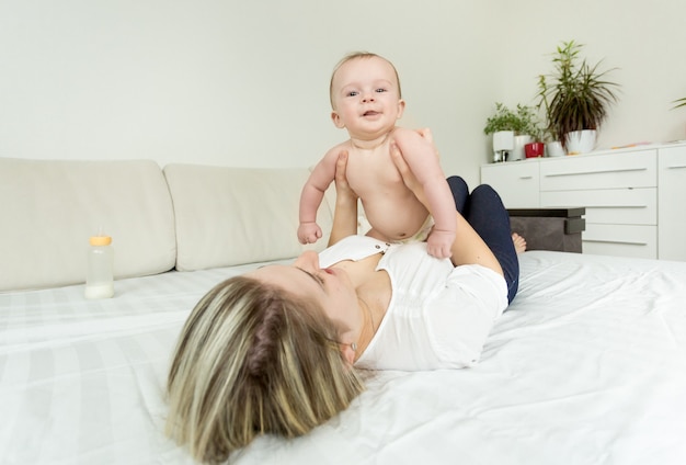 Portrait de jeune femme souriante jouant avec bébé sur lit