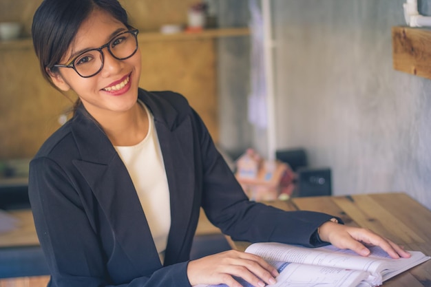 Portrait d'une jeune femme souriante avec un livre sur le bureau à la maison
