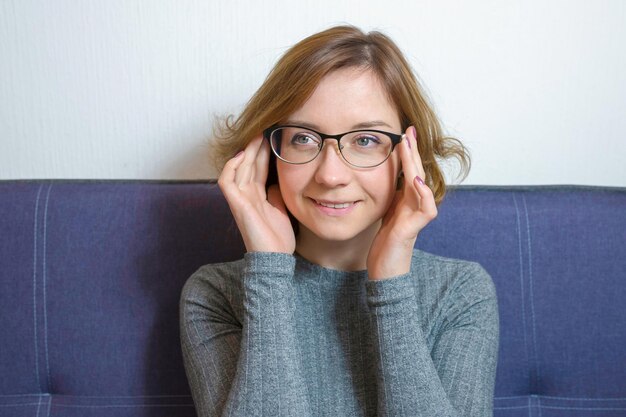 Portrait d'une jeune femme souriante avec des lunettes sur le canapé