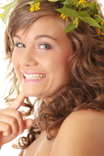 Portrait d'une jeune femme souriante portant des fleurs dans les cheveux sur un fond blanc