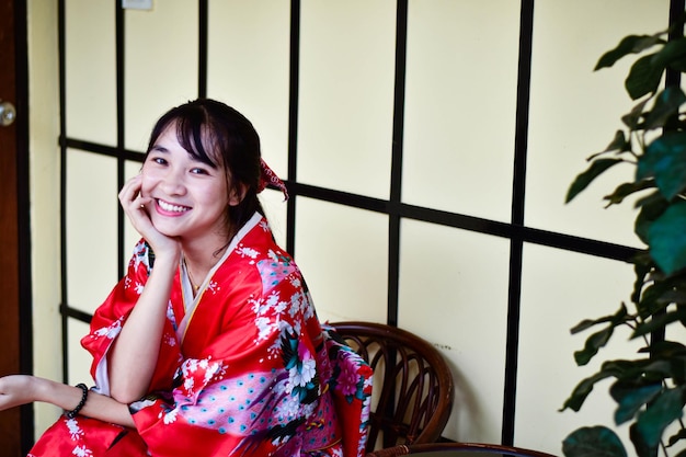 Portrait d'une jeune femme souriante portant un kimono assise sur une chaise