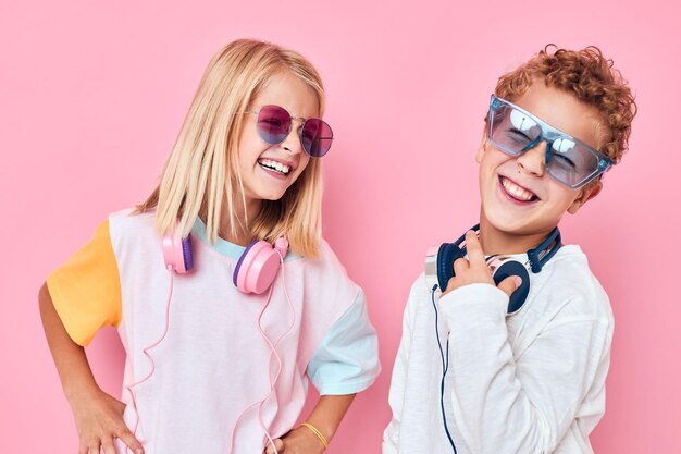 Photo portrait d'une jeune femme souriante portant des lunettes de soleil sur un fond rose