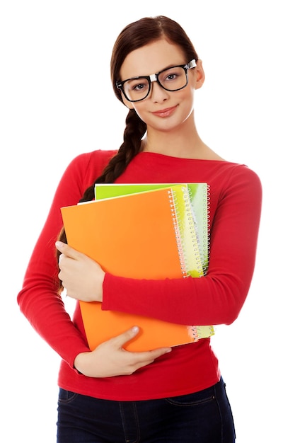 Portrait d'une jeune femme souriante portant des lunettes tenant des livres sur un fond blanc
