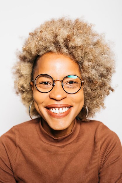 Portrait de jeune femme souriante portant des vêtements marron en se tenant debout sur fond blanc