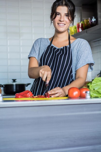 Photo portrait d'une jeune femme souriante préparant de la nourriture dans la cuisine à la maison