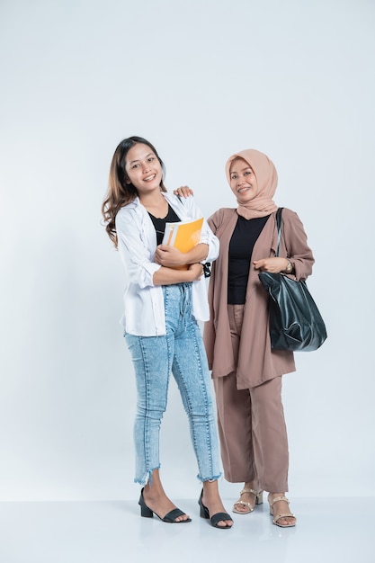 Portrait d'une jeune femme souriante rencontre un ami d'étude portant un sac et un livre sur un blanc isolé