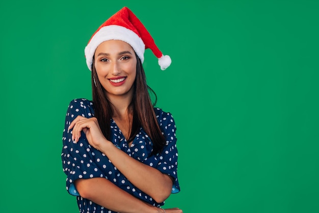 Portrait de jeune femme souriante en robe et chapeau de Père Noël La jeune fille croisa les bras