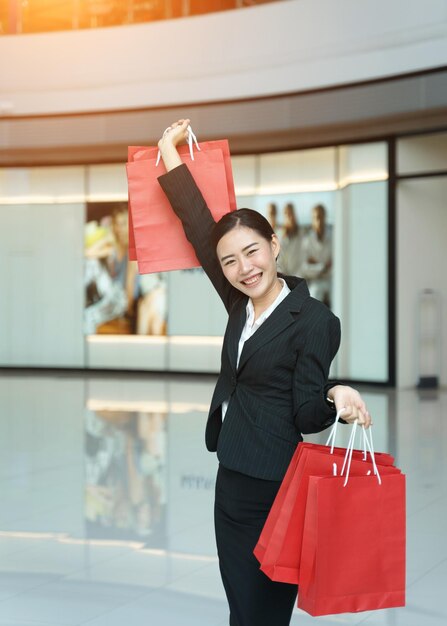 Photo portrait d'une jeune femme souriante tenant des sacs d'achat alors qu'elle se tient dans un centre commercial