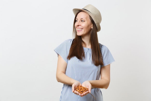 Portrait de jeune femme souriante tenir dans les mains des noix d'amandes non transformées brunes isolées sur fond blanc. Une bonne nutrition, une alimentation végétarienne végétalienne, un concept de régime alimentaire sain. Espace de copie