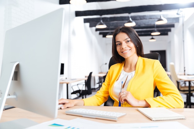 Portrait d'une jeune femme souriante utilisant un ordinateur portable au bureau