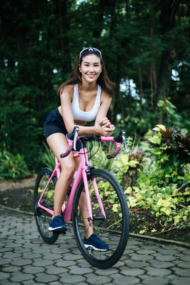 Photo portrait d'une jeune femme souriante avec un vélo sur la route