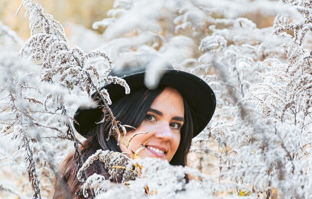 Photo portrait d'une jeune femme souriante en vêtements chauds et chapeau plantes de mise au point sélective