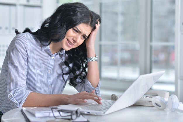 Portrait d'une jeune femme stressée à l'aide d'un ordinateur portable