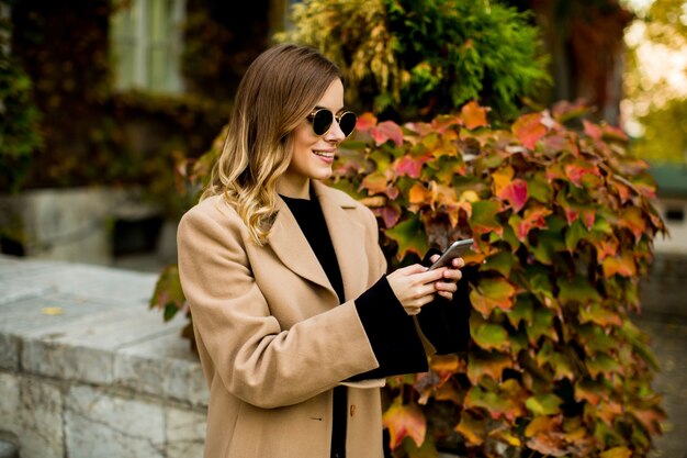 Portrait de jeune femme avec téléphone portable à l&#39;automne en plein air