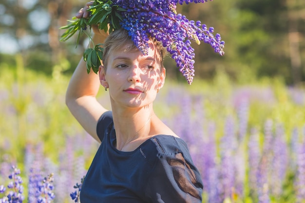 Portrait de jeune femme tenant un bouquet de fleurs de lupin marchant dans la prairie d'été Une fille élégante profite d'un temps ensoleillé