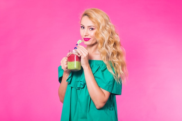 Portrait de jeune femme tenant et buvant un délicieux smoothie vert