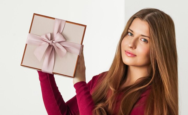 Photo portrait d'une jeune femme tenant un cadeau sur un fond blanc