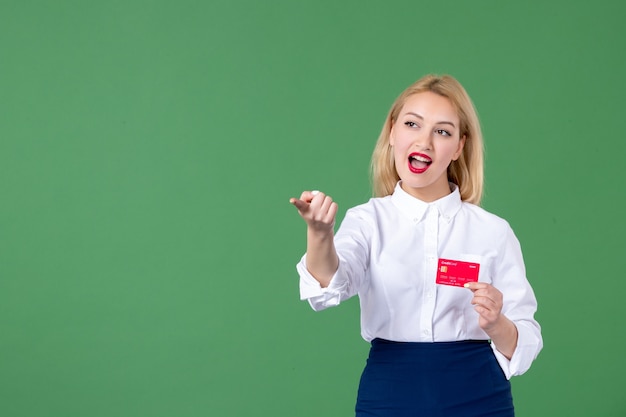 Portrait de jeune femme tenant une carte de crédit mur vert banque d'argent de l'école de commerce