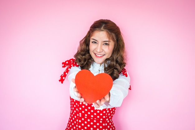 Portrait de jeune femme tenant un coeur rouge devant elle