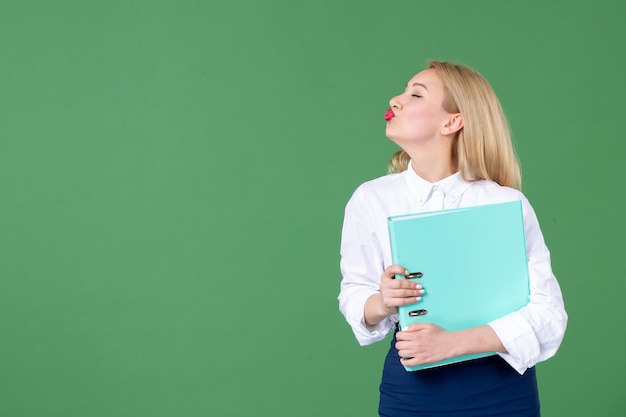 portrait de jeune femme tenant des documents mur vert les enseignants travaillent le travail des élèves de l'école