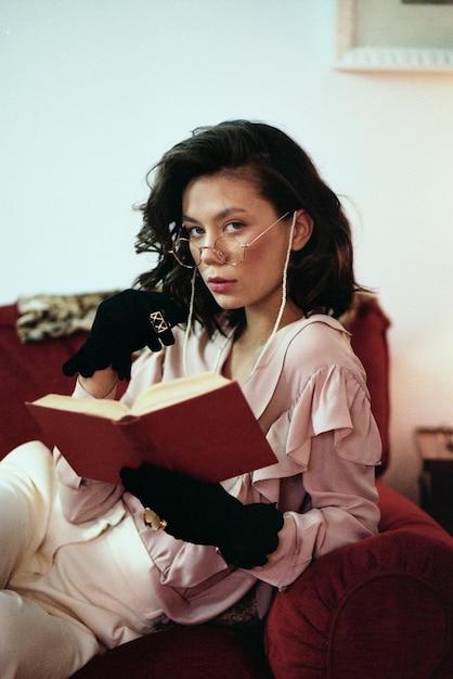 Photo portrait d'une jeune femme tenant un livre assise sur le canapé à la maison