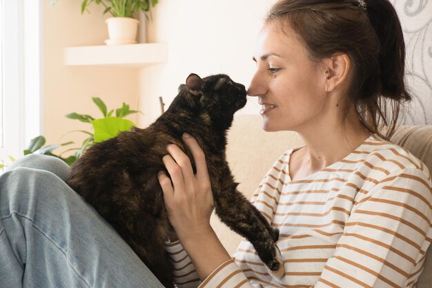 Photo portrait d'une jeune femme tenant un mignon chat noir la femelle embrasse son mignon chaton