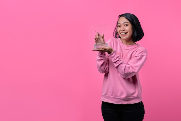 Portrait d'une jeune femme tenant une statue de récompense reçoit une surprise agréable et excitée