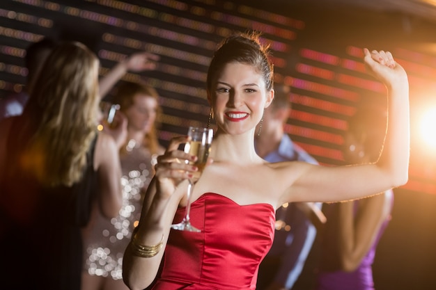Portrait de jeune femme tenant un verre de champagne en dansant