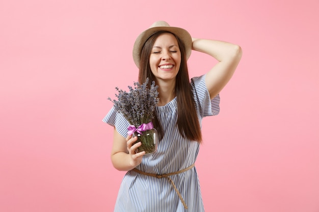 Portrait d'une jeune femme tendre et heureuse en robe bleue, chapeau tenant un bouquet de belles fleurs de lavande violettes isolées sur fond rose tendance vif. Concept de vacances de la Journée internationale de la femme.