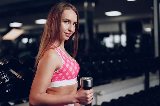 Portrait d'une jeune femme en tenue de sport posant dans une salle de sport