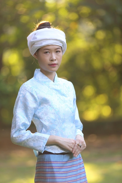 Portrait de jeune femme thaïlandaise avec une robe traditionnelle thaïlandaise dans un temple thaïlandais avec arbre et lever de soleil