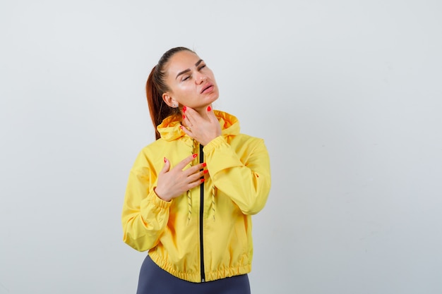 Portrait de jeune femme touchant la peau de son visage en veste jaune et regardant la charmante vue de face