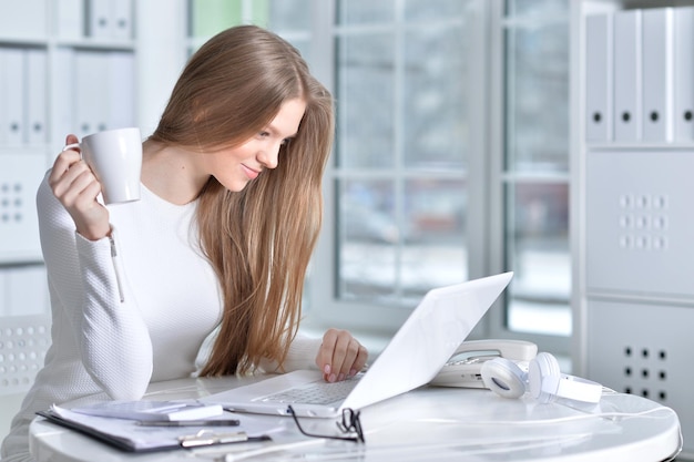 Portrait de jeune femme travaillant au bureau à l'aide d'un ordinateur portable