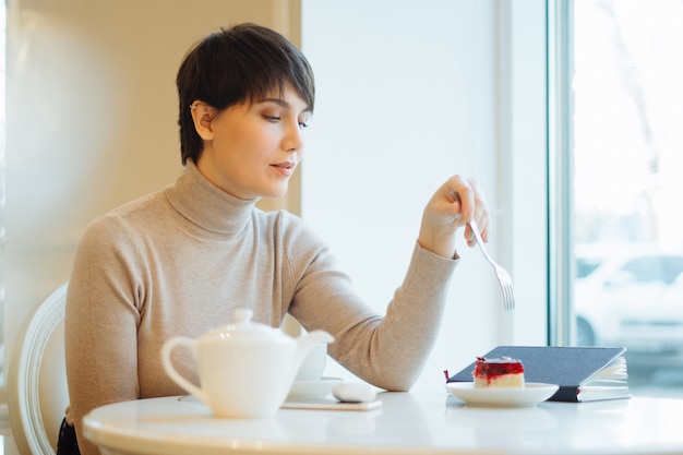 Portrait de jeune femme très souriante, manger un gâteau au café du centre commercial