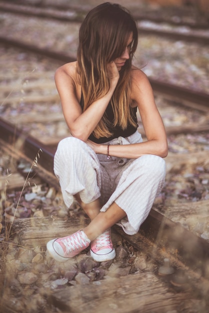 Photo portrait d'une jeune femme triste, assis à l'extérieur songeur sur la voie ferrée.