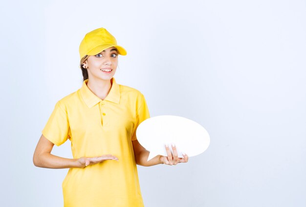 Portrait d'une jeune femme en uniforme jaune tenant une bulle vide vide.