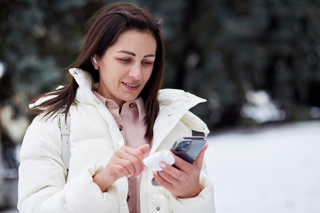 Portrait d'une jeune femme utilisant des écouteurs sans fil en plein air Freelance travaillant à distance Cours en ligne apprendre la langue dans l'application en discutant avec des collègues ou des amis Nouvelle normalité