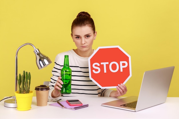 Photo portrait d'une jeune femme utilisant un ordinateur portable sur une table sur un fond jaune