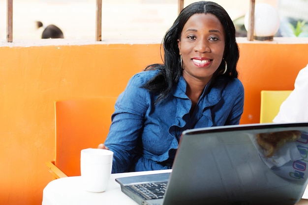 Portrait d'une jeune femme utilisant le téléphone alors qu'elle est assise sur la table