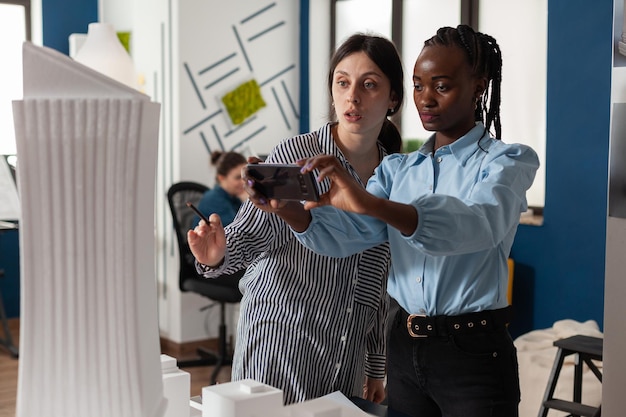 Photo portrait d'une jeune femme utilisant un téléphone portable alors qu'elle se tient au bureau