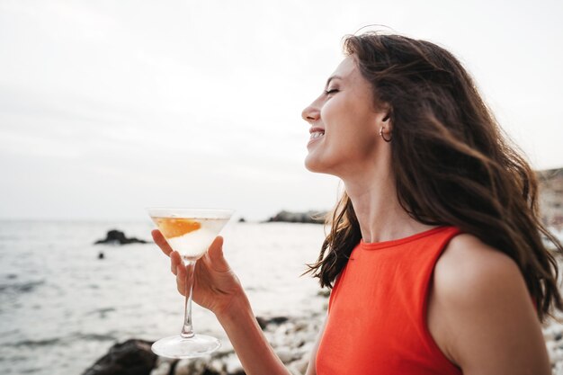 Portrait de jeune femme avec un verre à cocktail au frais sur une plage