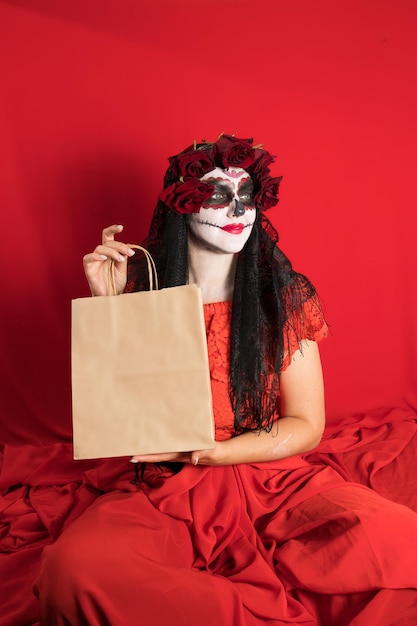 Portrait d'une jeune femme vêtue d'une robe rouge et d'un maquillage traditionnel de crâne de sucre pour la célébration de Dia de los Muertos le Jour des Morts