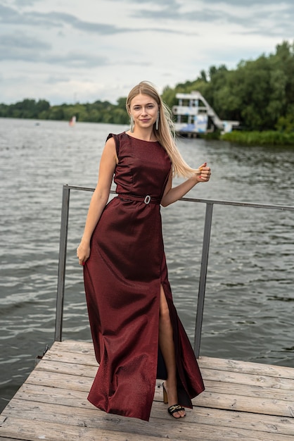 Portrait de jeune femme vêtue d'une robe rouge près de l'étang, détendez-vous et profitez d'une chaude journée d'été, style de vie