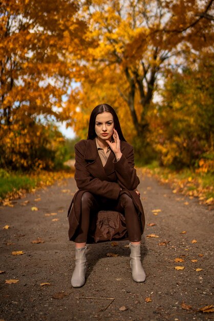 Portrait d'une jeune femme avec un vieux fauteuil dans un manteau brun en automne