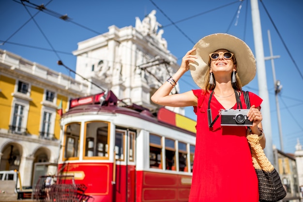 Portrait d'une jeune femme voyageant près du vieux tramway touristique rouge sur la place du Commerce par temps ensoleillé dans la ville de Lisbonne, Portugal