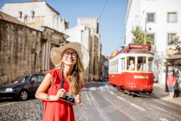 Portrait d'une jeune femme voyageur en robe rouge debout dans la rue avec le célèbre tramway touristique en arrière-plan à Lisbonne, Portugal