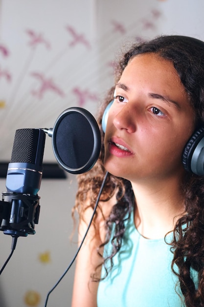 Portrait d'une jeune fille de 13 ans chantant à un microphone portant des écouteurs