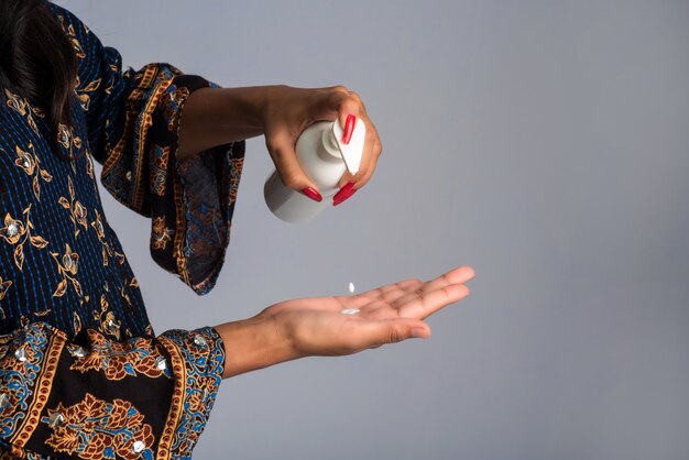 Portrait de jeune fille à l'aide ou montrant un gel désinfectant d'une bouteille pour le nettoyage des mains.