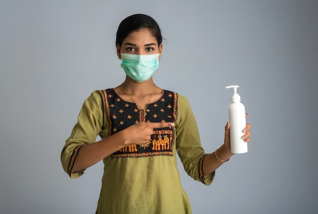 Portrait de jeune fille à l'aide ou montrant un gel désinfectant d'une bouteille pour le nettoyage des mains.